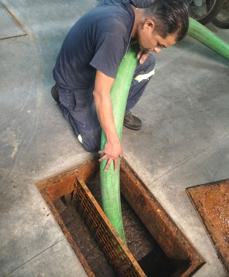 Operador realizando la succión de una trampa de grasa con manguera